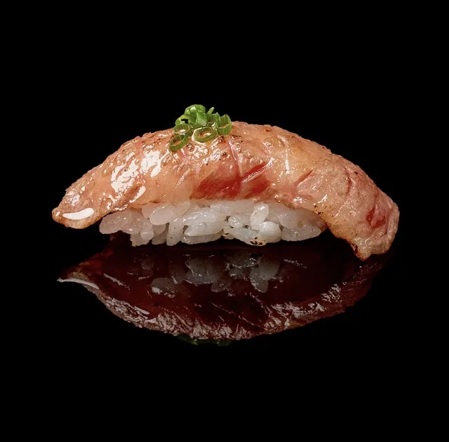 Nigiri di wagyu scottato con erba cipollina, su fondo nero