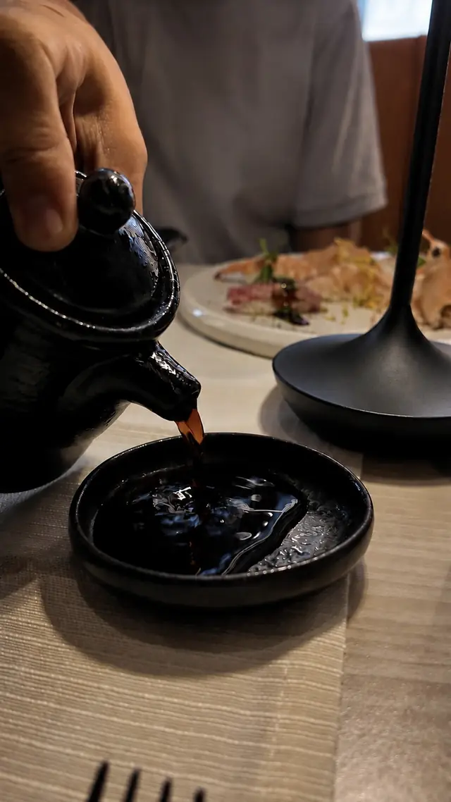 Salsa di soia versata nel piattino di ceramica nera